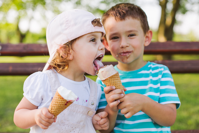 kids eating ice cream cones on a park bench